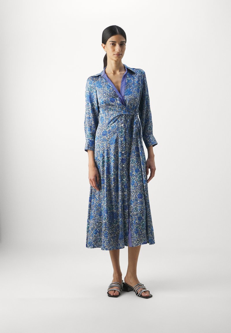 Blaues Wickelkleid mit Blumenmuster, Taillengürtel, langen Ärmeln und einem geknöpften Kragen. Verfügt über ein kontrastierendes gestreiftes Innenfutter und einen schwingenden Rock.