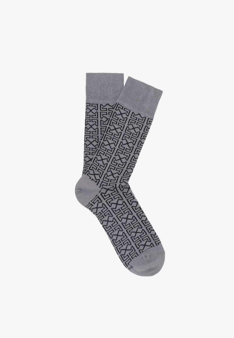 Grå sokker med et geometrisk sort mønster, ribbet kant og glat tekstur. Designet gentages over hele sokken.