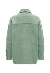 Πράσινο σακάκι από κορδόνι βαμβακιού με άνετη εφαρμογή, μυτερό γιακά και κουμπιά στο μανίκι. Υφή με ανάγλυφο ριμπ ύφασμα. Πλάγια όψη από πίσω.