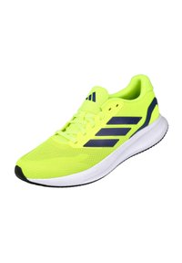 Zapatilla deportiva verde lima con rayas azul marino, parte superior textil, cuello acolchado y suela de goma negra. Diseñada para la comodidad y el rendimiento.