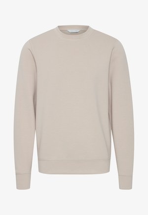 Heled beezhi värvi pusaka, ümmarguse kaelusega, pikkade varrukatega, ribaga mansettide ja alläärtega, valmistatud pehmest puuvillakangast. Muster või aksendit ei ole.