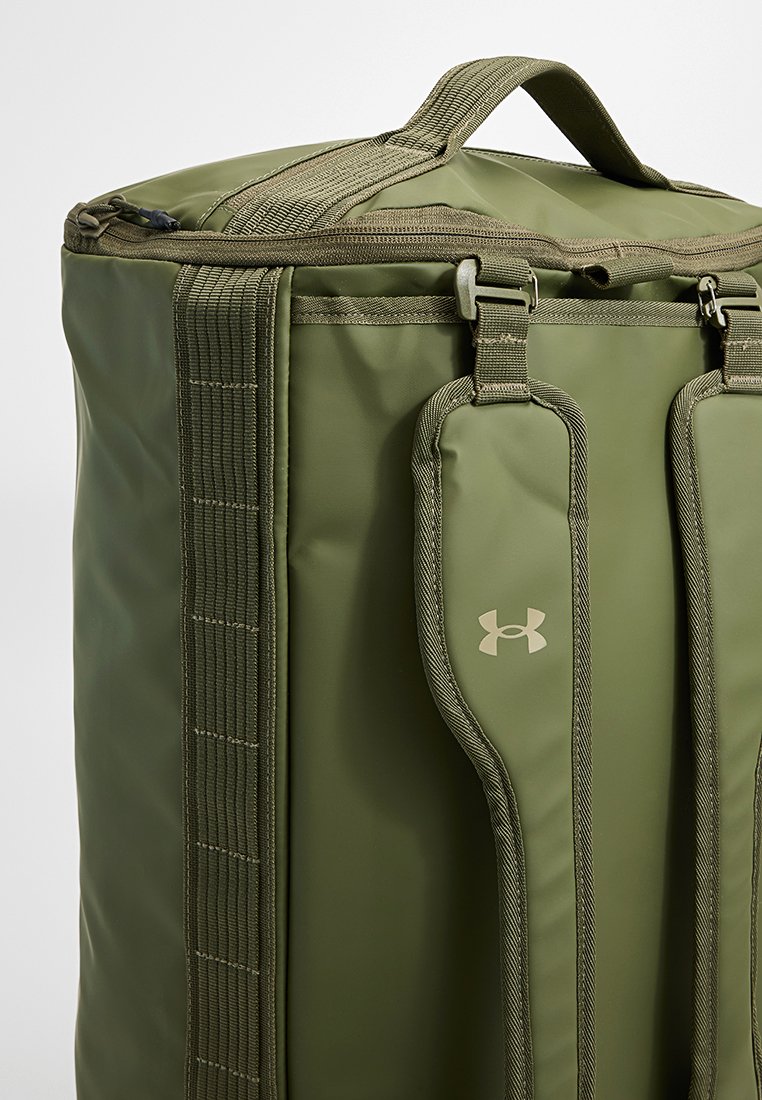 Olivgrüner Rucksack aus strapazierfähigem Material, mit einem oberen Griff, gepolsterten Trägern und einem Logo-Akzent an der Seite. Mit Reißverschluss.