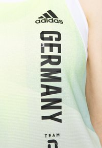 Adidas tanktop in lichtgroen met een gestructureerde afwerking. Heeft een grote zwarte "GERMANY"-print en logo op de bovenste linkerkant.