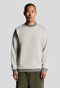 Lichtgrijs sweatshirt met een ronde hals, grijze accenten bij de kraag en manchetten, en een zachte textuur, gedragen boven olijfgroene broek.