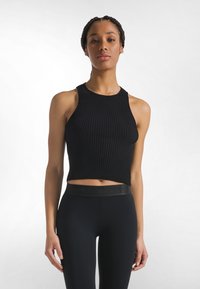 Sort ribbet crop tanktop med høj halsudskæring og ærmeløs design, kombineret med sorte leggings med en bred, mærket taljebånd.