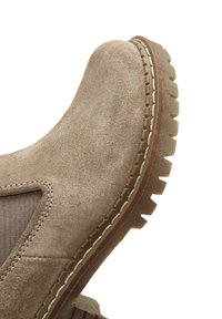 Stivale alla caviglia in suede tan con pannelli laterali elastici, suola in gomma texturizzata, cuciture a contrasto e punta rotonda.