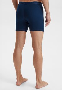 Marineblå bomuldsboxershorts med en tætsiddende pasform, elastisk talje og diskret logodetalje. Glat tekstur, længde til midten af låret.