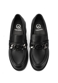 Mocassini in pelle nera con un accentuato motivo in catena d'argento e logo sul davanti. Texture liscia e design a punta arrotondata.