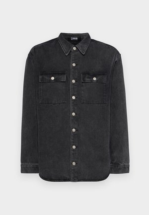 Czarna koszula dżinsowa z ostrym kołnierzykiem, zapięciem na guziki z przodu, dwiema kieszeniami na piersiach i srebrnymi akcentami. Długie rękawy z zapięciem na guziki.