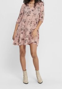 Robe florale rose avec décolleté en V, manches trois-quarts et design à volants ; dotée d'un tissu léger et d'une silhouette décontractée.