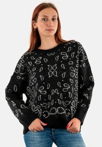 Zwarte gebreide trui met een witte bloemprint. Het ontwerp heeft een relaxte pasvorm, geribbelde manchetten en een brede halslijn. Zacht, gestructureerd materiaal.