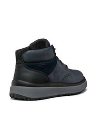 Zapatillas mid-top que presentan cuero y ante en color azul marino oscuro, un collar acolchado para mayor confort y una suela de goma gris gruesa con un patrón de tracción.