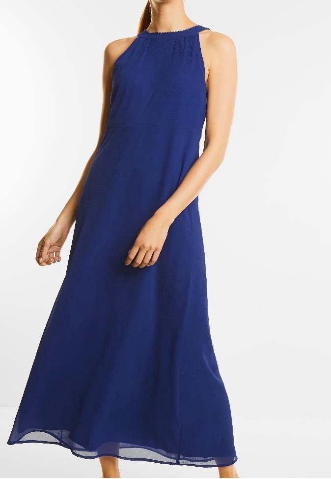 Femme portant une robe sans manches bleu marine, longue jusqu'aux chevilles, avec un col montant, debout devant un fond blanc uni.