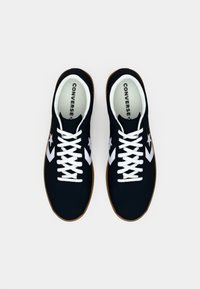 Pair of black Converse sneakers with white laces and star logo, brown soles, viewed from above on a white background.