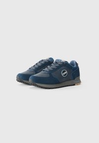 Donkerblauwe sneakers met een combinatie van suede en synthetische materialen, een gestructureerd oppervlak, vetersluiting en een rond logo aan de zijkant.