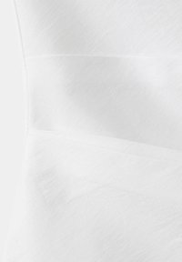 Gros plan d'un tissu blanc montrant une texture subtile et des lignes de couture horizontales.