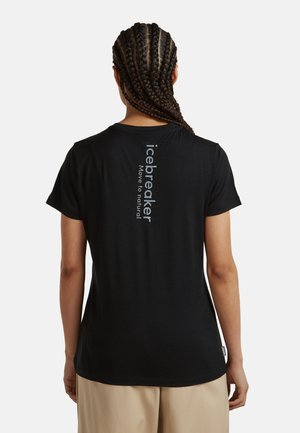 Person med fletninger set bagfra iført sort t-shirt med lodret "icebreaker Move to natural"-tekst på øverste del af ryggen.