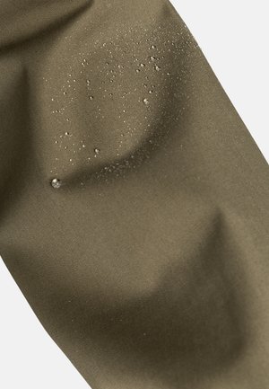 Vodoodolný olivovo-zelený materiál s viditeľnými kvapkami vody na hladkom povrchu, zdôrazňujúci odolnosť a vodoodpudivú štruktúru.