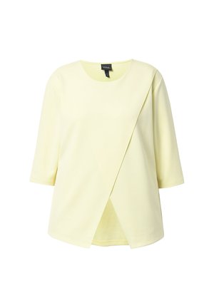 Vaaleankeltainen lyhythihainen pusero pyöreällä pääntiellä, epäsymmetrisellä etukerroksella ja rennolla istuvuudella.