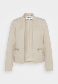 Beżowa marynarka z gładkiej tkaniny, o dopasowanym kroju, z kieszeniami na suwak oraz bez kołnierza. Wnętrze wyściełane.