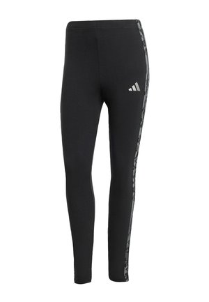 Leggings de sport noirs avec des rayures latérales en camouflage gris et un petit logo Adidas blanc sur la cuisse supérieure.