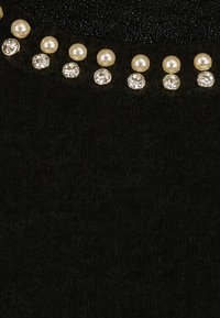 Top in tessuto nero con superficie texturizzata, decorato con perle e cristalli lungo la scollatura per un tocco di dettaglio in più.