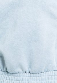 Tejido de algodón azul claro con una textura suave, que presenta una cinturilla elástica. Sin patrones ni diseños visibles.