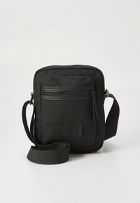 Sac bandoulière noir en tissu durable, avec fermeture éclair supérieure, poche avant zippée, sangle réglable et forme rectangulaire.