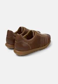 Scarpe in pelle marrone con una finitura strutturata, caratterizzate da una punta arrotondata, sei occhielli e una suola in gomma a contrasto con punti in rilievo.