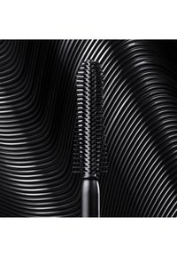 Svart hårborste med ett texturerat handtag och jämnt fördelade piggar, mot en vågig svart bakgrund. Slank och minimalistisk design.