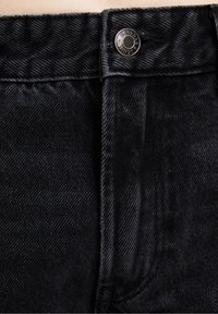 Black denim jeans featuring a smooth texture, silver button closure, and contrast stitching along the waistband and side seams.