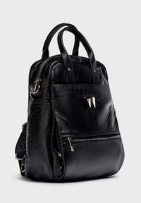 Sac à dos texturé noir avec double poignées, poche zippée à l'avant, tirettes de fermeture éclair en argent et logo métallique "W" sur le panneau avant.