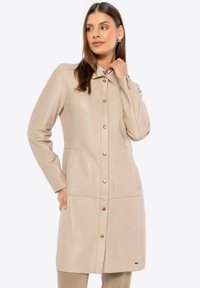 Beige leren jas met een kraag, zichtbare knopen en zijzakken. Heeft stiksel details en een rechte snit voor een perfecte pasvorm.
