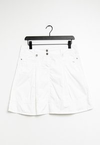 Jupe plissée blanche avec deux poches avant, boutons en métal à la taille, et une texture lisse semblable à du coton. Suspendue à un cintre en plastique noir.