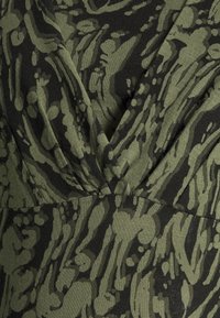 Ärmlös klänning med ett grönt och svart abstrakt mönster, V-hals och rynkade detaljer vid midjan. Tillverkad av mjukt tyg.