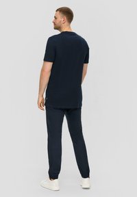 Marineblauw T-shirt met korte mouwen, gecombineerd met bijpassende broek, beide in een soepele katoenmix. Witte sneakers maken de outfit compleet.