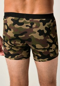 Boxer shorts para hombres en un patrón de camuflaje con tonos de verde, marrón y negro. Fabricados con una tela elástica y con una cinturilla negra.
