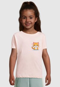 Lyserød t-shirt med korteærmer, der har en tegneserieagtig orange kat med en hvid mave, siddende på en blå overflade, omgivet af små lyserøde hjerter.