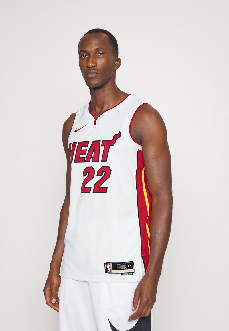 Balts basketbola krekls ar sarkaniem un dzelteniem akcentiem. Uzdrukāts "HEAT" treknā sarkanā fontā un numurs "22". Iekļauts Nike logo un NBA birka.