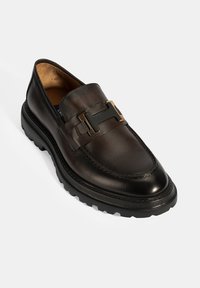 Schwarze Lederloafers mit dicker Gummisohle, dekorativem goldfarbenem Schnallenverschluss und glattem Obermaterial mit Steppnähten.