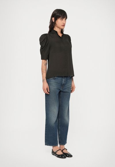 Mustruudega must pluus volangvarrukatega, kombineeritud laia säärega tuhmisinistes teksapükstega ja mustade naelutatud platvormkingadega.