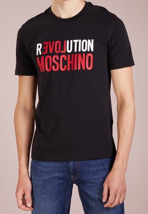 Camiseta negra de algodón con un texto audaz en rojo y blanco que dice "REVOLUTION MOSCHINO". Mangas cortas y cuello redondo. Textura suave, ajuste casual.