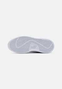 Semelle de chaussure avec un design en caoutchouc blanc, featuring un motif en chevron et une étiquette non marquante. Logo Puma sur le côté.