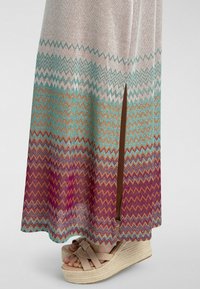 Maxidress med spaghetti-stropper i vævet stof med et zigzag-mønster; har en sideslids, i farverne teal, orange og fuchsia.