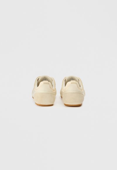 Μπεζ αθλητικά παπούτσια με λείο δερμάτινο φινίρισμα και μαλακές σουέτ λεπτομέρειες, με λαστιχένια σόλα και μινιμαλιστικό πίσω σχέδιο.