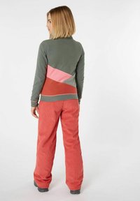 Maglione in pile verde, rosa e ruggine con design a blocchi di colore; abbinato a pantaloni in velluto a coste rosa. Presenta polsini a coste e una silhouette aderente.