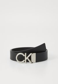 Cinturón de cuero negro con una hebilla de metal plateado con las letras "CK". El cinturón es liso y plano, con un diseño minimalista.