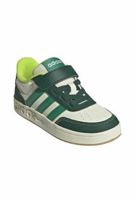 Sneaker verde e bianco con tomaia in pelle texturizzata, dotata di tre strisce verdi, un cinturino in velcro e una suola in gomma.