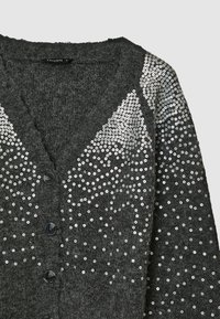Cardigan grigio con una texture pelosa, chiusura a bottoni e un motivo a gradiente di paillettes argento sul davanti.