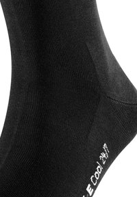 Chaussette noire de cheville en matériau extensible et lisse. Présente une texture côtelée et du texte blanc imprimé sur le côté. Pas de motifs ou accents distincts.